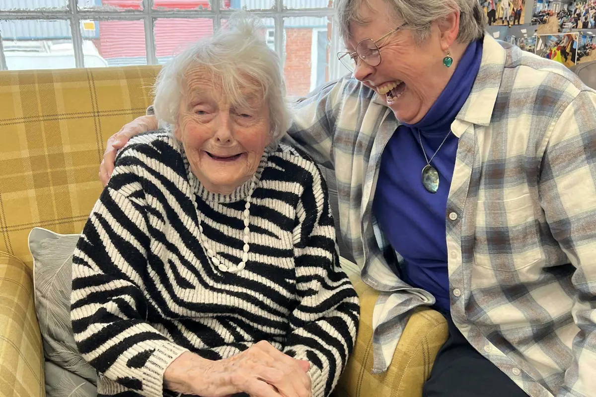 Peggy laughing as she is hugged by her daughter at Old Silk Works club
